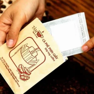 cà phê phin giấy nữ hoàng hoặc cà phê phin giấy lắng đọng được cầm bới bàn tay trên phông nền gỗ